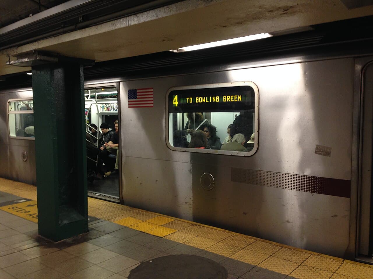 An R142 subway car of the 4 train standing at 59th Street, doors open, its lit destination sign reading 4 to Bowling Green.